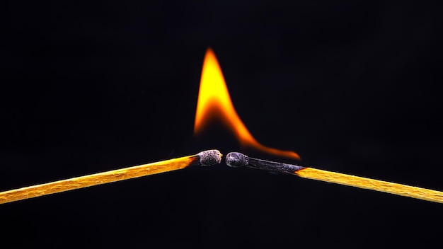 Foto fósforo ardente em um fundo preto calor e luz da chama do fogo