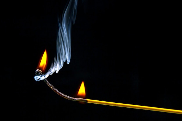 Fósforo de madeira piscando e queimando em um fundo escuro fechado Fogo brilhante e fumaça de uma árvore em chamas