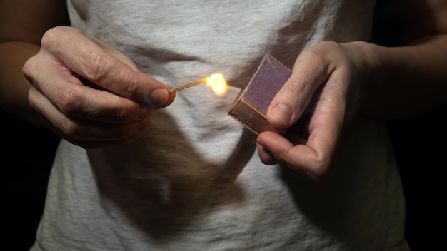 Fósforo de iluminación de mujer en la oscuridad