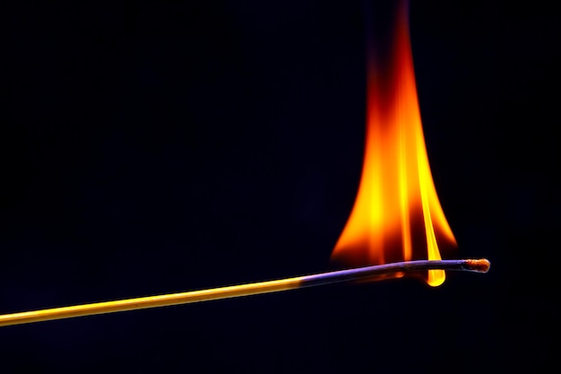 Fósforo de madera ardiendo en un primer plano de fondo oscuro fuego de árbol ardiendo