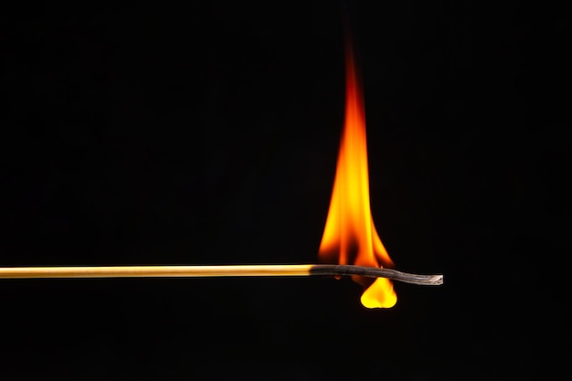 Fósforo de madera ardiendo en un primer plano de fondo oscuro fuego de árbol ardiendo