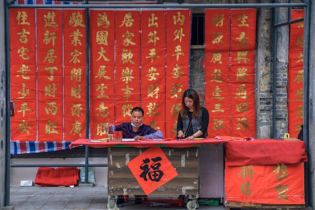 Foshan, província de guangdong, china. 8 de fevereiro de 2021. um calígrafo está escrevendo dísticos do festival da primavera para as pessoas. é o costume mais comum e importante na celebração do ano novo chinês.