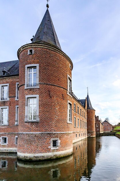 Foto foso que rodea el castillo alden biesen del siglo xvi torre circular paredes de ladrillo, ventanas y techo a dos aguas vista desde el patio exterior día nublado en bilzen limburg bélgica