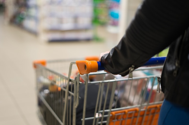 Foto abstrata de mulher carregando um carrinho ou carrinho no supermercado.