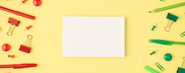Foto acima de papel cartão monocromático verde e vermelho papelaria lápis caneta clipes de papel e ponta de feltro isolado no fundo amarelo