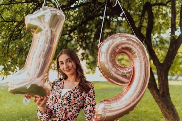 Una foto de una adolescente fotografiada junto a un número de cumpleaños en el parque