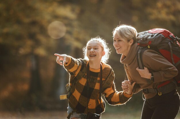 Una foto de una adolescente y su madre caminando juntas por el bosque en otoño.