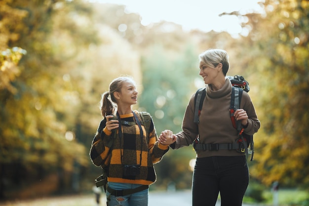 Una foto de una adolescente y su madre caminando juntas por el bosque en otoño.