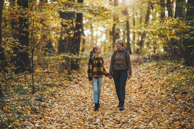 Foto una foto de una adolescente y su madre caminando juntas por el bosque en otoño.