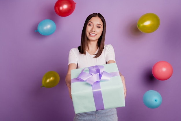 Foto de adorable encantadora dama agradable alegre mantenga dar caja presente globos caen sobre fondo púrpura