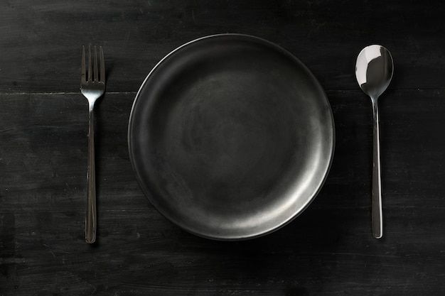 Foto aérea Configuração de mesa de jantar preta moderna com garfo de prato preto vazio e colher plana