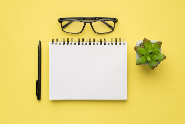 Foto aérea da planta de óculos de notebook e caneta preta isolada no fundo amarelo