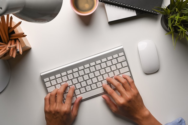 Foto aérea das mãos do empresário digitando no teclado sem fio.