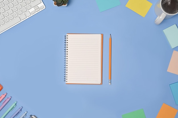 Foto aérea de caderno vazio e material de escritório sobre fundo azul.