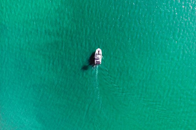 Foto aérea de drone de barco de alta velocidade cruzando na baía exótica tropical com mar esmeralda