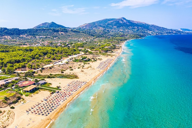 Foto aérea de drone de vista superior da praia de Banana com belas ondas do mar de água turquesa e guarda-chuvas vermelhos Fundo de viagem de férias Mar Jônico Ilha de Zakynthos Grécia