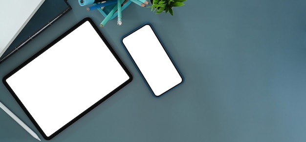 Foto aérea de tablet digital, celular e material de escritório na mesa azul. tela em branco para sua mensagem de texto ou conteúdo de informação.