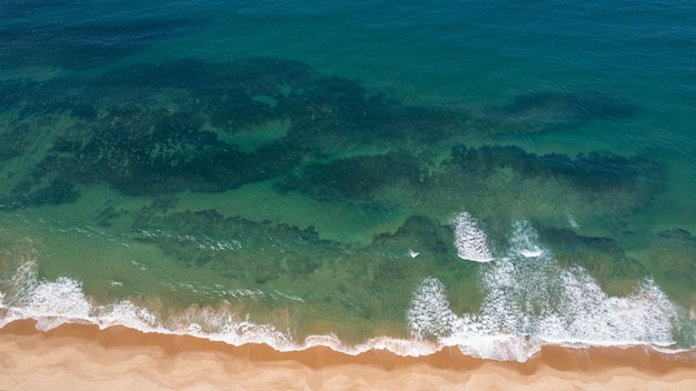 Foto aérea de um drone sobrevoando a praia mostrando a faixa de areia e o mar no Brasil