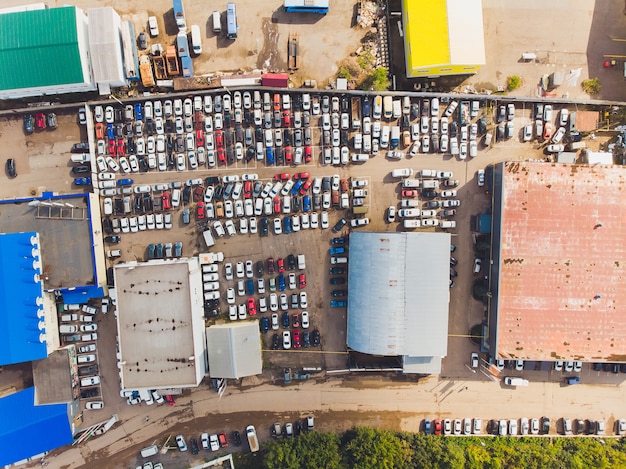 Foto aérea de um pequeno lote temporário de carro para armazenar carros novos para revenda e revendedores de carros que não têm espaço livre para armazenamento de cima para baixo em alta altitude.