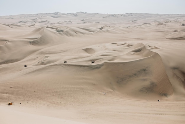 Foto aérea de uma paisagem de um deserto arenoso sob um céu azul