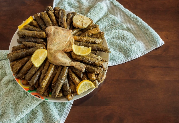 Foto aérea de uma refeição tradicional árabe de folhas de uva com carne de frango servida com limões