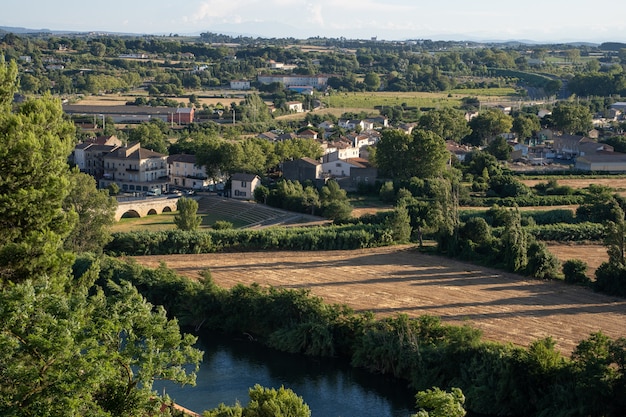 Foto aérea de uma vila rural cercada por campos e um rio. Narbonne na França