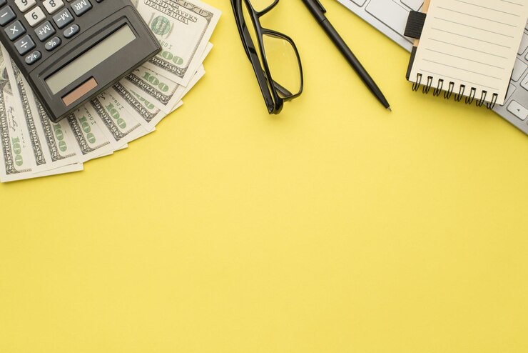 Foto aérea do caderno de óculos de caneta de dinheiro calculadora e teclado isolado no fundo amarelo