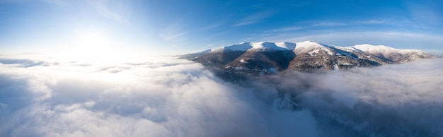 Foto aérea do majestoso nascer do sol nas montanhas O vale entre as montanhas está coberto de neblina e é iluminado pelos raios quentes do sol nascente Montanhas cobertas de floresta natural