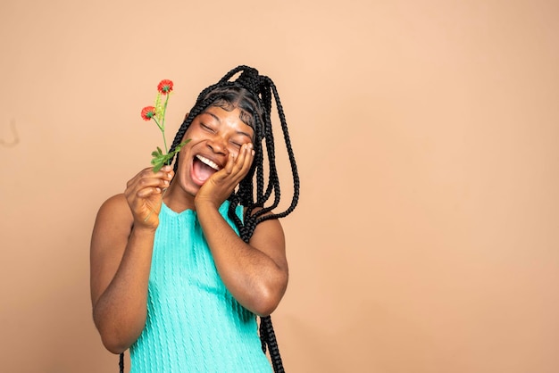 Foto de una agradable optimista mujer africana emocionada sosteniendo flores mirando el espacio vacío sintiendo