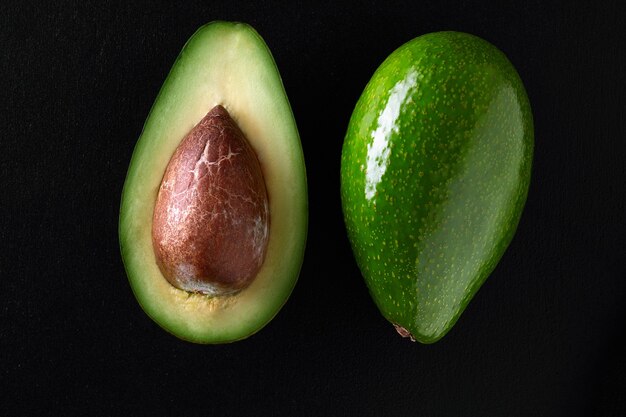 Foto de aguacates frescos cortados por la mitad sobre el fondo negro