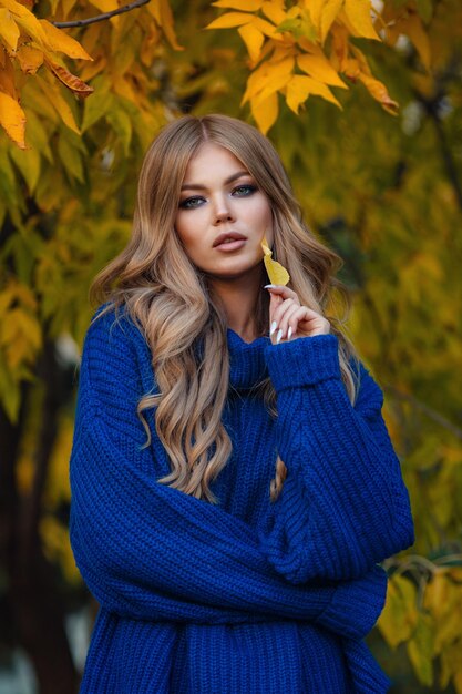 Foto al aire libre de moda de mujer hermosa con cabello rubio en traje elegante posando en el parque de otoño