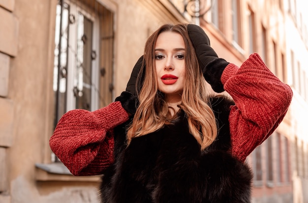 Foto al aire libre del modelo femenino de moda caminando por la ciudad en vacaciones de invierno.