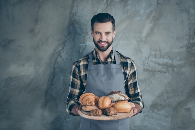 Foto de alegre cocinero atractivo atractivo guapo positivo cocinero sonriendo toothily en camisa a cuadros con cerdas pared de color gris aislado muro de hormigón