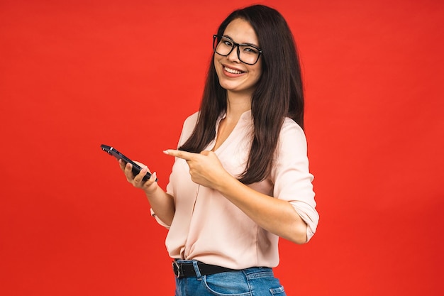 Foto de una alegre y hermosa mujer joven de negocios usando un teléfono móvil aislado sobre un fondo rojo Espacio para texto