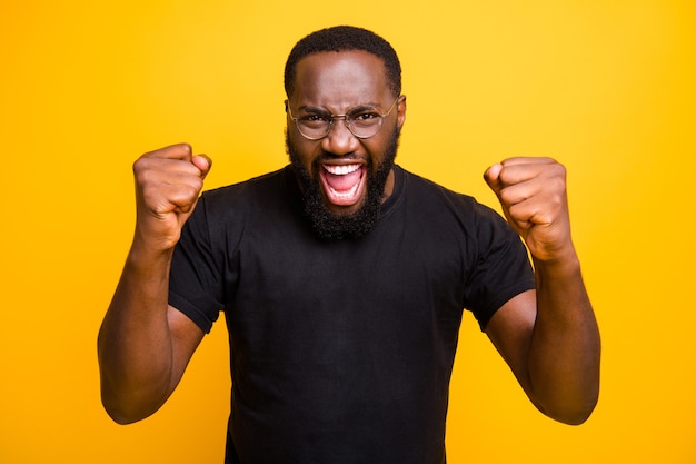 Foto de alegre hombre gritando de moda expresando groseras emociones de felicidad en la cara en camiseta gafas aislado pared de colores vibrantes