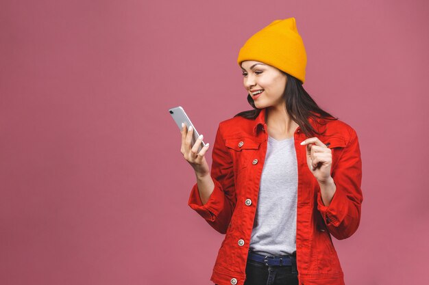 Foto de alegre linda hermosa joven hablando por teléfono móvil aislado sobre la pared de pared rosa.