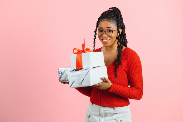 Foto de alegre niña positiva sostener paquete de regalo aislado fondo de color rosa.