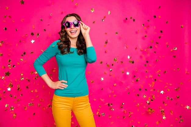 Foto foto de alegre positivo agradable bastante fascinante joven femenino femenino sosteniendo anteojos gafas en pantalones amarillos pantalones aislados de color brillante fondo fucsia