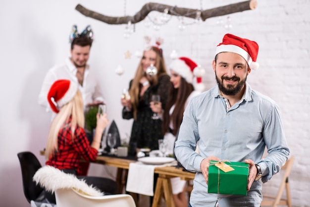 Foto de amigos felices disfrutando de las vacaciones se centran en el hombre en primer plano con un sombrero rojo de Navidad