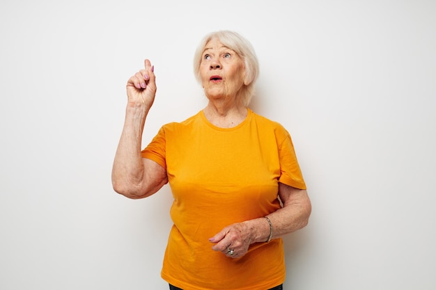 Foto de anciana jubilada en una camiseta amarilla posando emociones de primer plano