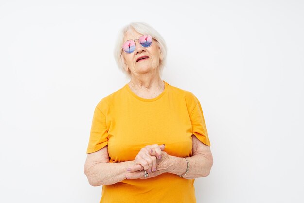 Foto de una anciana jubilada con una camiseta amarilla posando con un fondo claro
