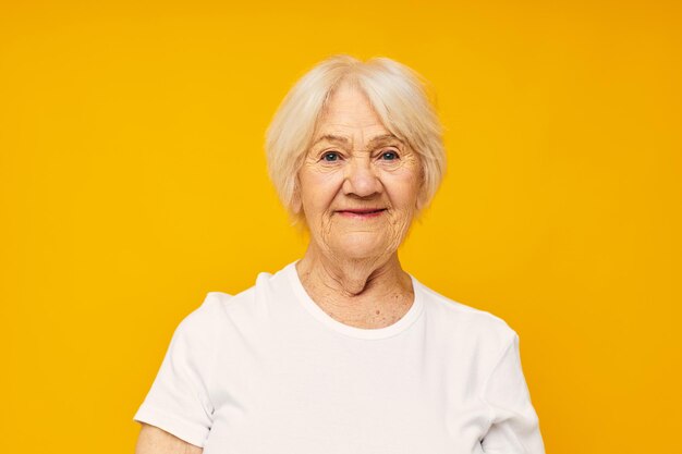 Foto de anciana jubilada en camiseta blanca posando divertido fondo amarillo