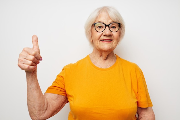 Foto de anciana jubilada con camiseta informal y anteojos de fondo claro