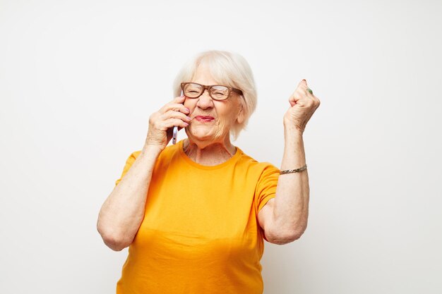 Foto de anciana jubilada con gafas de moda con un teléfono inteligente en la mano emociones de primer plano