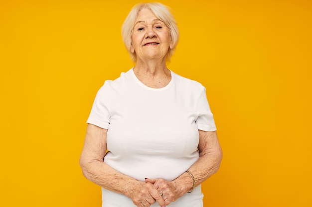 Foto de una anciana jubilada con gestos casuales de camiseta con las manos de fondo amarillo