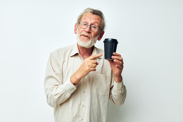 Foto de un anciano jubilado con barba gris en una camisa y anteojos de fondo claro