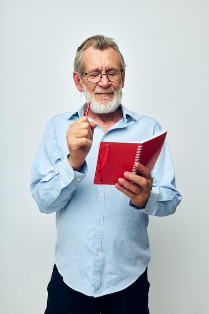 Foto de un anciano jubilado con un cuaderno rojo y un bolígrafo de fondo aislado