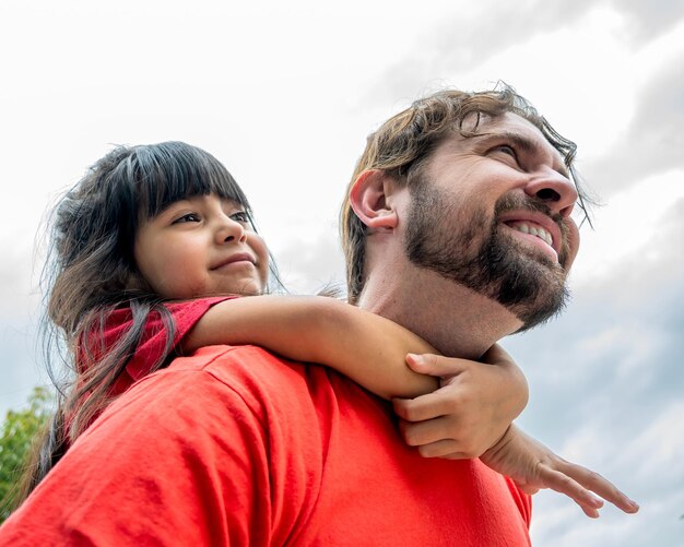 Foto foto de ángulo bajo de un padre latino con su hija abrazándolo por la espalda