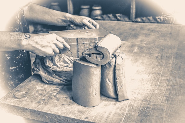 Foto antiga vintage. Preparação de argila branca para o trabalho. Corte de camadas de peças de argila para esculpir na oficina de um oleiro Close-up. Folhas de argila torcidas na velha mesa de madeira em cerâmica. Ucrânia