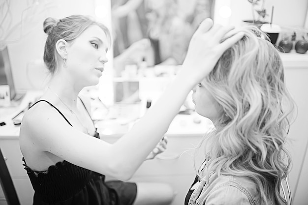 foto antigua en blanco y negro de una chica con maquillaje profesional / maquillaje estricto en la cara de una hermosa modelo profesional en un salón de belleza